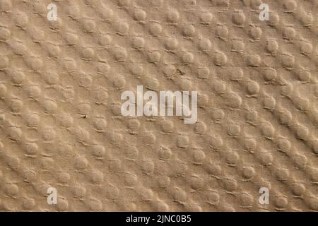 Nahaufnahme einer Oberfläche aus braunem Karton mit einem Muster diagonal ausgerichteter Knöpfe Stockfoto