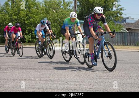 Weibliche Radrennfahrer fahren auf einer Runde eines Criterium, einem Radrennen, bei dem die Frauen auf den Straßen der Stadt mit ihren Fahrrädern um einen Rundkurs fahren. Stockfoto