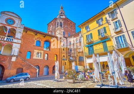 PAVIA, ITALIEN - 9. APRIL 2022: Blick auf den mittelalterlichen Backsteinpalast Broletto und die hohe Kuppel der Kathedrale im Hintergrund, am 9. April in Pavia, Italien Stockfoto