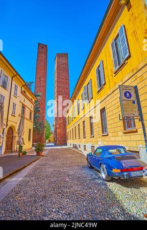 PAVIA, ITALIEN - 9. APRIL 2022: Spazieren Sie am 9. April in Pavia, Italien, entlang einer engen mittelalterlichen Straße zu den herausragenden Türmen auf der Piazza Leonardo da Vinci Stockfoto