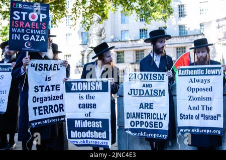 London, Großbritannien. 10.. August 2022. Mitglieder von Neturei Karta, einer Gruppe ultraorthodoxer Juden, die sich gegen den Zionismus einsetzen, halten bei einer Kundgebung für Palästina gegenüber der Downing Street Schilder ab, die den Staat Israel kritisieren. Mindestens 47 Palästinenser, darunter 16 Kinder, wurden bei einem dreitägigen Bombardement von Gaza durch israelische Truppen namens Operation Truthful Dawn getötet und Hunderte weitere verletzt. Kredit: Mark Kerrison/Alamy Live Nachrichten Stockfoto