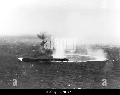 Der japanische Flugzeugträger Shōkaku, der mit hoher Geschwindigkeit und harten Dreharbeiten unterwegs war, hat Bombenangriffe erlitten und ist während der Schlacht am Korallenmeer im Mai 1942 in Brand geraten. Stockfoto