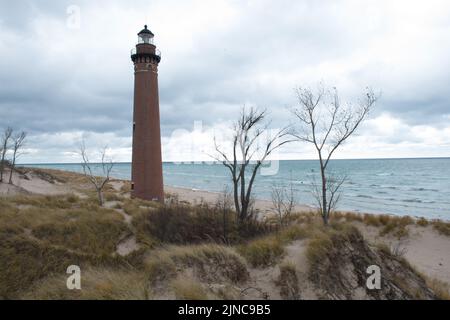 Der historische Little Sable Point Lighthouse liegt in den umliegenden Sanddünen unter stürmischem Herbsthimmel in der Nähe von Pentwater, Michigan, USA. Stockfoto