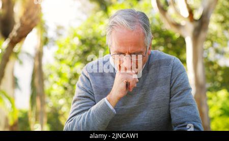 Sind Sie zufrieden mit den Entscheidungen, die Sie getroffen haben? Ein älterer Mann, der nachdenklich auf den Park schaut? Stockfoto