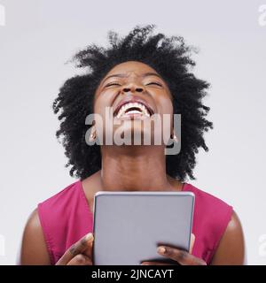 Genau darauf habe ich gewartet. Studioaufnahme einer jungen Frau mit einem digitalen Tablet vor grauem Hintergrund. Stockfoto