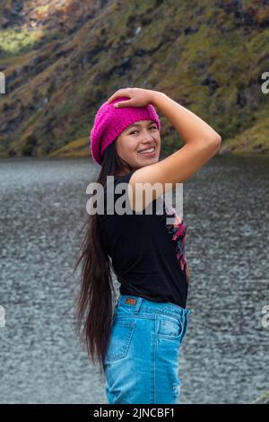 Eine vertikale Aufnahme eines attraktiven Wanderers, der neben einem ruhigen See in den wunderschönen Bergen steht Stockfoto