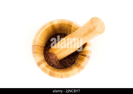 Gemahlenes getrocknetes Sumpfbeerpulver in einem Holzmörtel und Stößel Stockfoto