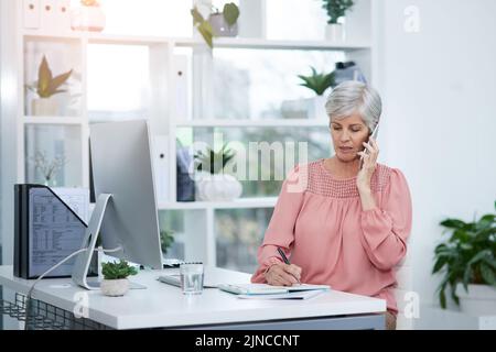 Achten Sie immer auf Details im Umgang mit Kunden. Reife Geschäftsfrau nimmt einen Anruf an ihrem Schreibtisch bei der Arbeit. Stockfoto