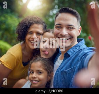 Lassen Sie uns unsere niedlichen Familienmomente einfangen. Beschnittenes Porträt einer glücklichen Familie, die ein Selfie im Park macht. Stockfoto