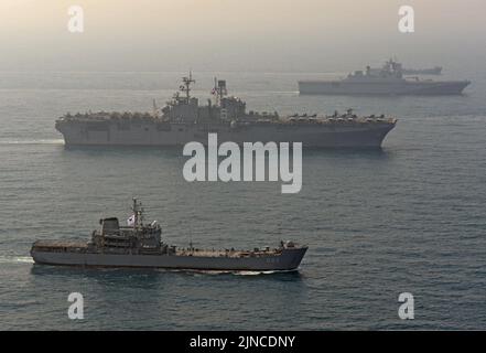 Das amphibische Angriffsschiff USS Bonhomme Richard (LHD 6), Mitte, durchschifft das Ostchinesische Meer mit dem südkoreanischen amphibischen Angriffsschiff ROKS Dokdo (LPH 6111), rechts, und dem südkoreanischen amphibischen Dock 140327 Stockfoto