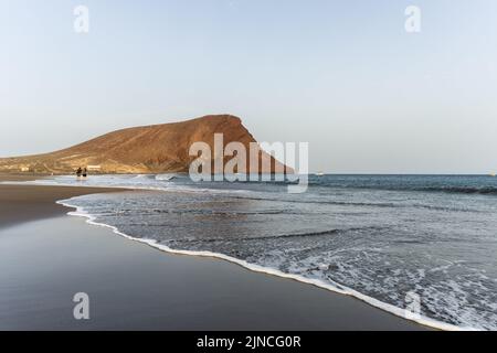 Allgemeiner Blick auf den Strand von La Tejita mit Blick auf den Berg Montana Roja auf Teneriffa. Die wichtigsten Hotspots auf Teneriffa, auf den Kanarischen Inseln, füllen sich im Sommer mit Touristen. Stockfoto