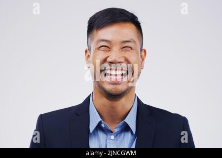 Es gibt keinen Grund, dass das Geschäft ernst ist. Studioporträt eines hübschen jungen Geschäftsmannes, der vor einem grauen Hintergrund lacht. Stockfoto