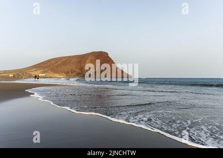 Teneriffa, Spanien. 26.. Juli 2022. Allgemeiner Blick auf den Strand von La Tejita mit Blick auf den Berg Montana Roja auf Teneriffa. Die wichtigsten Hotspots auf Teneriffa, auf den Kanarischen Inseln, füllen sich im Sommer mit Touristen. (Foto von Hugo Amaral/SOPA Images/Sipa USA) Quelle: SIPA USA/Alamy Live News Stockfoto