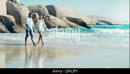 Der Strand ist für Süße gemacht. Die ganze Aufnahme eines glücklichen jungen Paares, das einen Spaziergang am Meer macht. Stockfoto