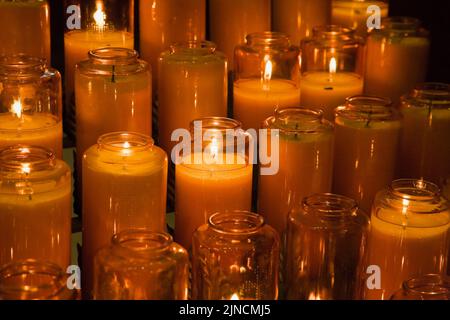 Orangefarbene Votivkerzen in der Kirche. Stockfoto