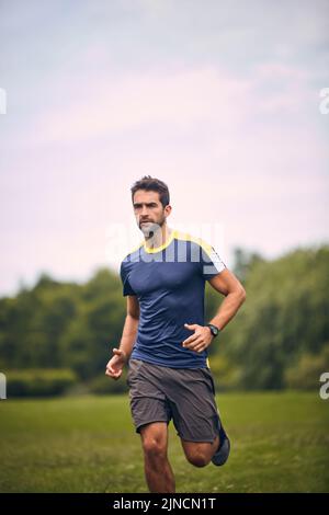 Ich fühle, wie gut Bewegung für mich ist. Ein sportlicher Mann mittleren Alters, der in einem Park läuft. Stockfoto