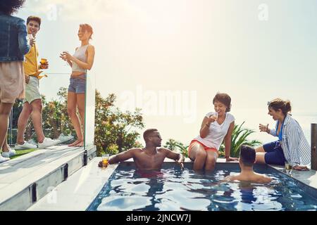 Eine Gruppe von Freunden, die Getränke trinken und sich im Urlaub am Pool amüsieren. Stockfoto