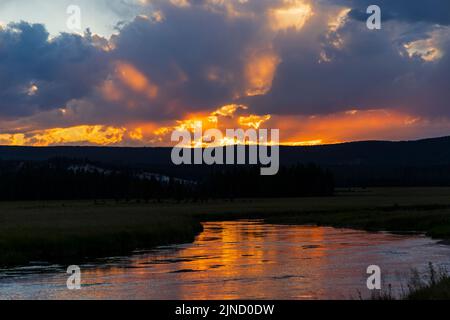 Das orangefarbene Licht des Sonnenuntergangs spiegelt sich auf dem Gibbon River östlich der Madison Junction Area im Yellowstone National Park, Teton County, Wyoming, USA Stockfoto