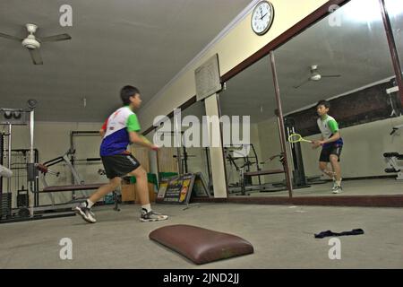 Im Jaya Raya Badmintonclub in Jakarta, Indonesien, übt ein junger Badmintonathlet verschiedene Schläge vor einem großen Spiegel. Stockfoto