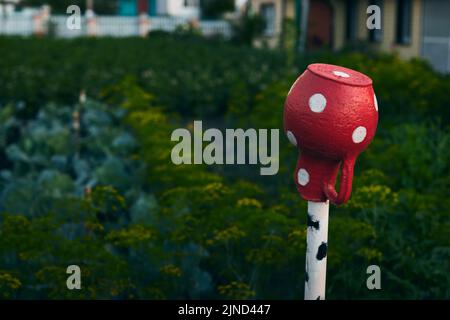 Im Sommer ein roter Keramikkrug auf einer Stange auf dem Land. Ländliche Idylle. Vorderansicht. Stockfoto