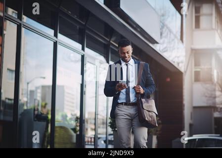 Wir können uns einmal im Büro unterhalten. Ein hübscher junger Geschäftsmann benutzt ein Handy in der Stadt. Stockfoto