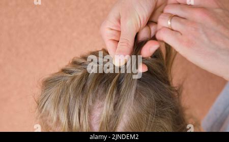 Mutter kämmt Vorschule Töchter Haare Zöpfe Hause kleine Mädchen lange blonde Haare Stockfoto