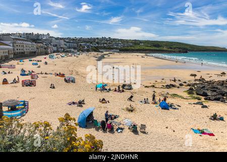 Menschen genießen einen sonnigen Sommertag am Porthmeor Beach in St. Ives, Cornwall, England. Stockfoto