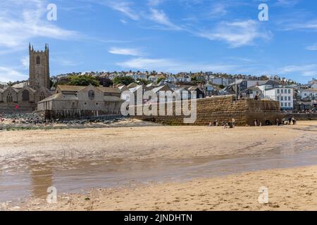 Blick vom Strand auf St. Ives, mit dem Pier auf der rechten Seite und der Pfarrkirche St. Ives auf der linken Seite. Stockfoto