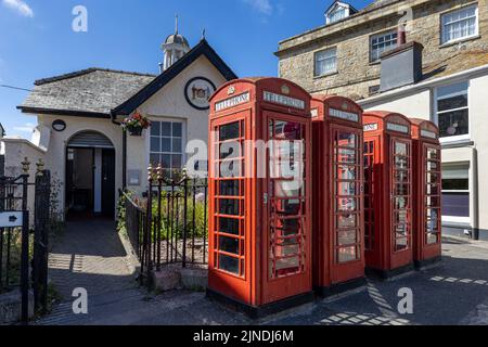 Vier traditionelle rote Telefonzellen vor den öffentlichen Toiletten im Stadtzentrum von Truro, Cornwall. Stockfoto