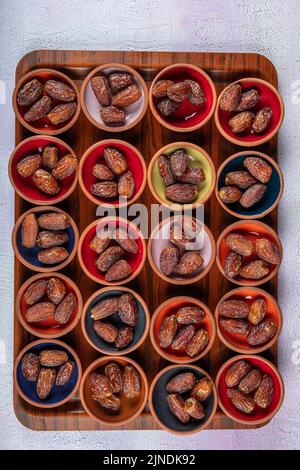 Eine frische Dattelpalme und eine trockene Dattelpalme auf einem Holztablett. Datteln (Hurma) auf einem Tablett vor dem Iftar im Ramadan. Stockfoto