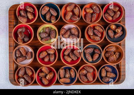 Eine frische Dattelpalme und eine trockene Dattelpalme auf einem Holztablett. Datteln (Hurma) auf einem Tablett vor dem Iftar im Ramadan. Stockfoto