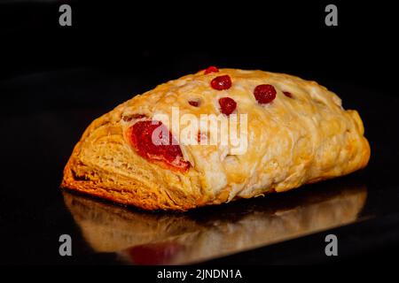 Ein gebackenes Brötchen mit roter Erdbeermarmelade im Elektroofen: Nahaufnahme Stockfoto