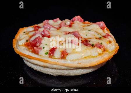 Hausgemachte Mini-Pizza Backen auf Blech im elektrischen Ofen, schwarzer Hintergrund Stockfoto