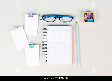 Leeres Notizbuch mit Stift, Papier und Brille auf grauem Hintergrund, Ideenfindung, Schreiben einer Botschaft, Arbeitsplatz-Schreibtisch, Home Office Stockfoto