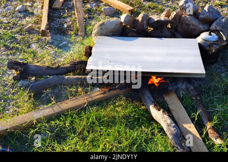 Marmor auf Lagerfeuer zum Kochen und Teekannen am Feuer im Freien Stockfoto