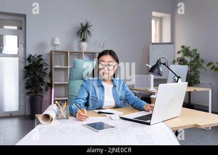 Junge schöne asiatische Frau Architektin Designer trägt Brille am Desktop-Computer arbeiten und Zeichnung mit Bleistift, arbeiten an Projekt. Stockfoto