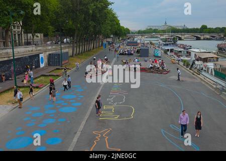 Weite Aufnahme von Menschen, die am Ufer der seine hängen und die Kunstinstallationen genießen. Schöner Sommertag im Freien in Paris, Frankreich. Stockfoto