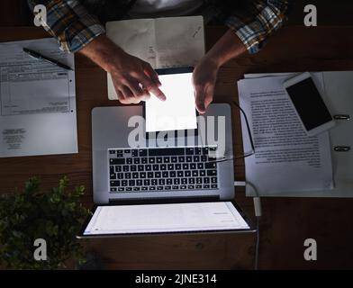 Laptop und Tablet in den Händen eines Mannes, der spät in der Nacht im Büro von oben arbeitet. Termin und Überstunden an einem Schreibtisch mit Technik und Papierarbeit Stockfoto