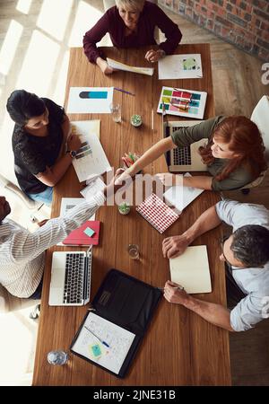 Händedruck, Zustimmung und Begrüßung des Teams kreativer Designer während eines gemeinsamen Meetings. Overhead-Ansicht einer vielfältigen Gruppe von Künstlern oder Stockfoto