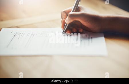 Nahaufnahme von Geschäftshänden einer Person, die den Papierkram ausfüllt. Hand eines individuellen Schreibstests, Informationen oder einer Umfrage auf Papier auszufüllen Stockfoto