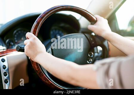 Hände eines Fahrers auf einem Lenkrad in einem Auto für Reisen, Fahren oder eine Roadtrip. Fahren Sie mit dem Taxi, dem Taxi oder mit dem Mitfahrdienst Stockfoto
