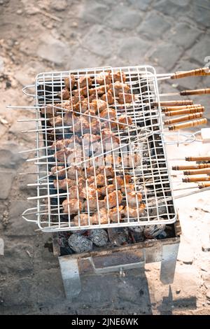 Grill wird bei einem Picknick verwendet, um Fleisch darauf zuzubereiten Stockfoto