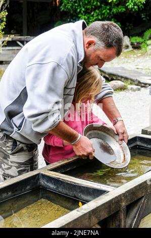Ein Vater und eine Tochter versuchen ihr Geschick beim Goldwaschen im lebenden Museum einer alten Goldgräberstadt in Shantytown, südlich von Greymouth am We Stockfoto