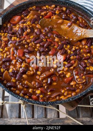 Veganer Bohneneintopf, Chili sin Carne in einer Pfanne mit Spatel auf Holzhintergrund Stockfoto