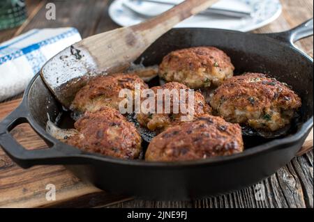 Dänische Fleischbällchen, Frikadeller in einer Bratpfanne auf einem Holztisch Stockfoto