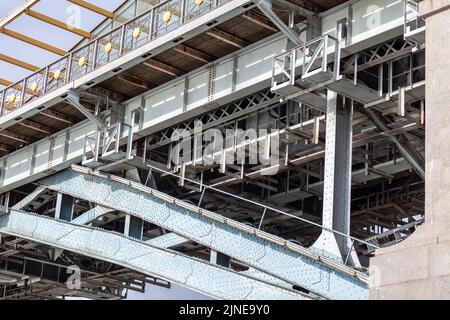 Metallstangen Fußgängerbrücke mit vielen Nieten. Kraftvolle Eisenbrücke, Blick von unten große Eisenniete. Ein Fluss fließt unter dem Br Stockfoto