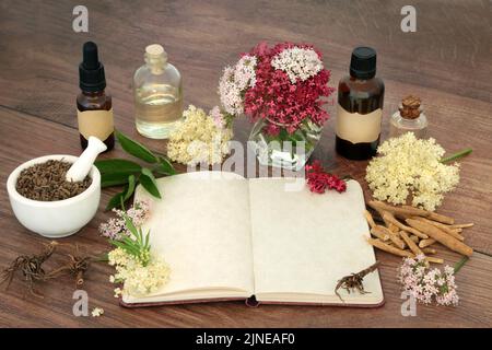 Stressreduzierende pflanzliche Medizin mit Baldrianwurzel, Ashwagandha und Holunderblüten und Notizbuch für Formeln. Für stressreduzierende natürliche Blume Stockfoto