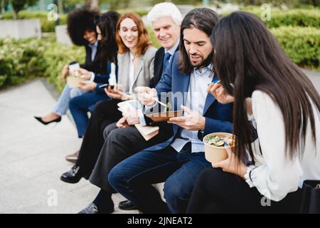 Multiethnische Geschäftsleute, die eine Mittagspause im Freien vom Bürogebäude aus machen – Fokus auf das richtige Männergesicht Stockfoto
