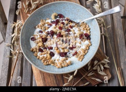 Gepuffter Hafer mit Preiselbeeren, Cashewkernen und Joghurt in einer Schüssel Stockfoto
