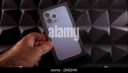Paris, Frankreich - 28. Sep 2021: Persönliche Perspektive männliche Hand hält Unboxing neuen neuesten Apple Computers Handy iPhone Smartphone Technologie Hintergrund Stockfoto